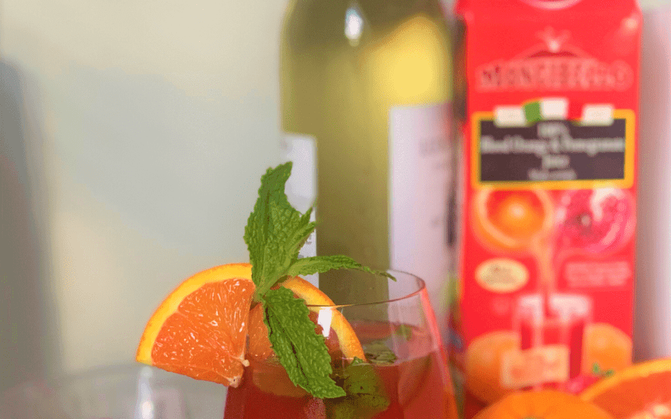 ingredients for white wine spritzer recipe, wine, pomegranate seeds, and blood orange juice