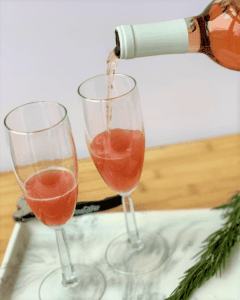 pouring rose wine into glasses on top of guava kombucha