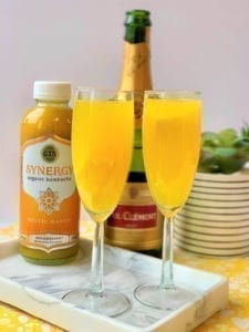 two mango mimosa cocktails with kombucha and sparkling wine