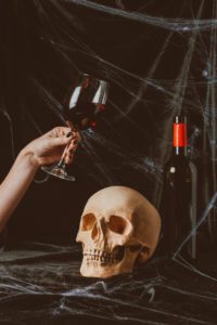 hand holding red wine glass with spooky setting