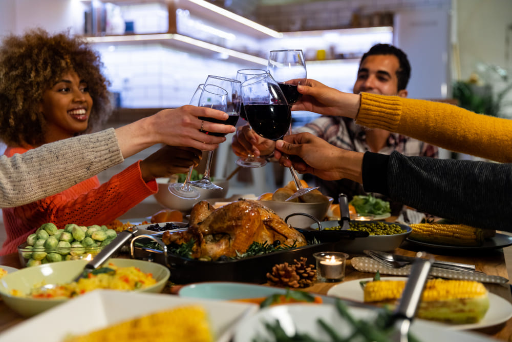 people celebrating thanksgiving with red wine and turkey