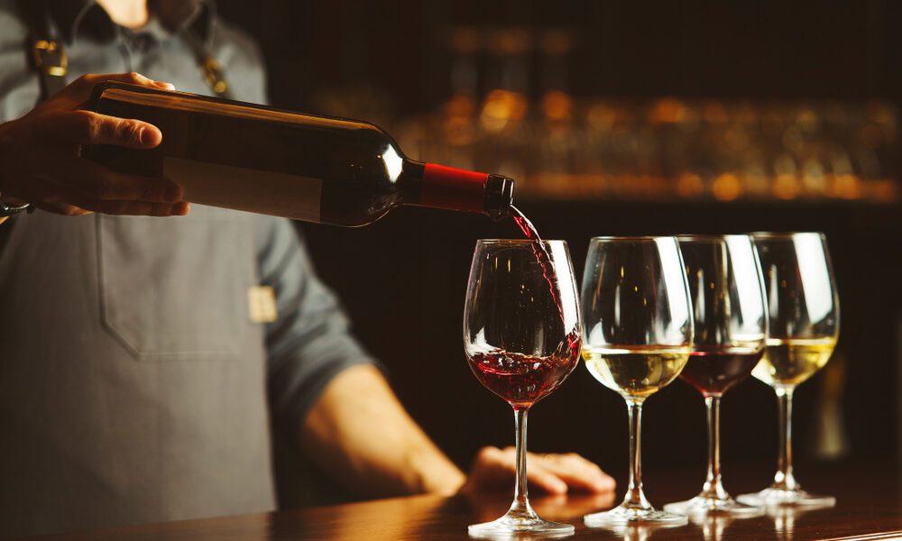 bartender pouring 4 glasses of wine from wine bottle