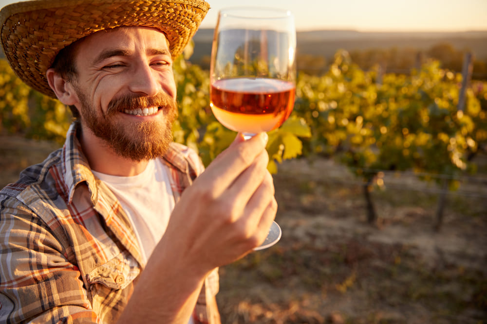 winemaker holding a glass of rose in vineyard